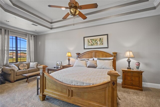 carpeted bedroom with a tray ceiling, ornamental molding, and ceiling fan