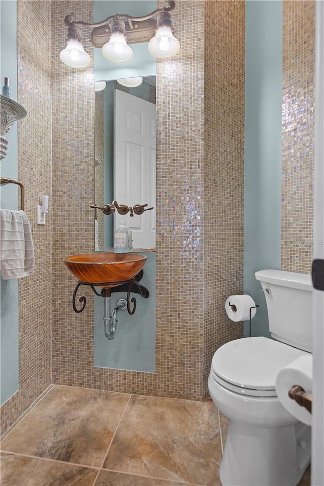 bathroom with tile patterned floors, toilet, and tile walls