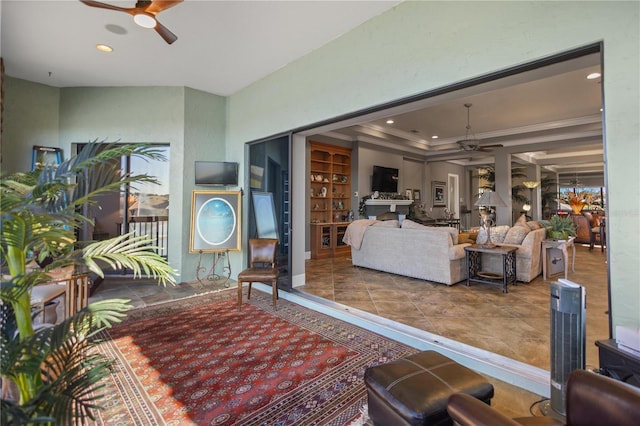 living room with a tray ceiling, crown molding, and ceiling fan