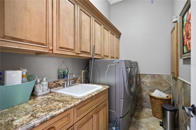 washroom with tile walls, sink, cabinets, and independent washer and dryer