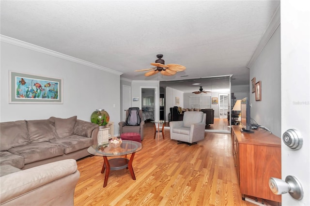 living area with ornamental molding, ceiling fan, light wood-style flooring, and a textured ceiling