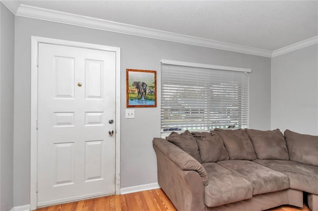 living area with ornamental molding, light wood-style flooring, and baseboards