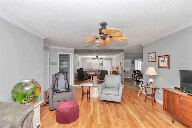 living area with light wood-style flooring, a textured ceiling, ornamental molding, and a ceiling fan