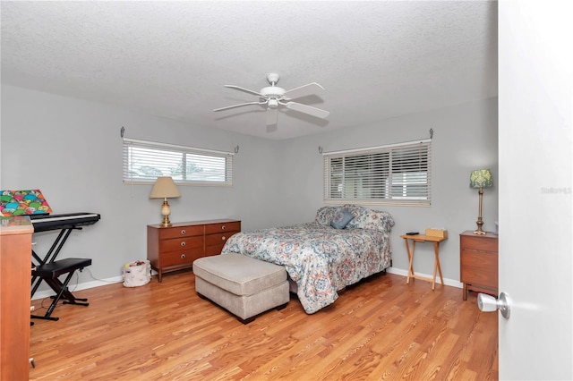 bedroom featuring light wood-type flooring, baseboards, and a textured ceiling