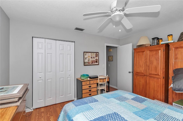 bedroom featuring a textured ceiling, a ceiling fan, visible vents, light wood-style floors, and a closet