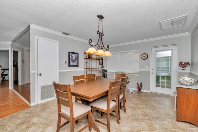 dining room featuring visible vents, a textured ceiling, and ornamental molding