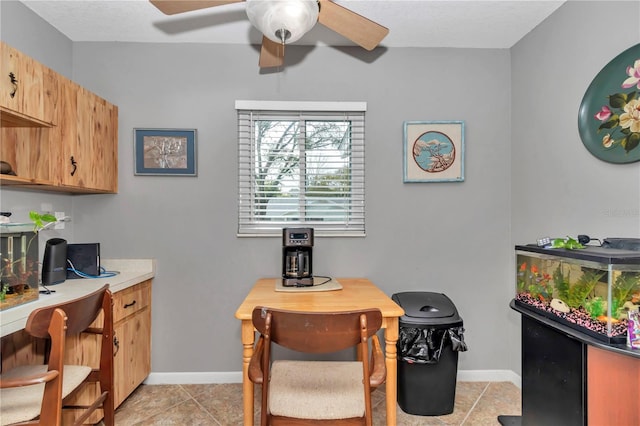 interior space with a ceiling fan, light tile patterned flooring, and baseboards