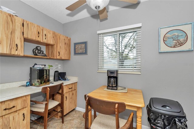 office space featuring light tile patterned floors, built in study area, a ceiling fan, and baseboards