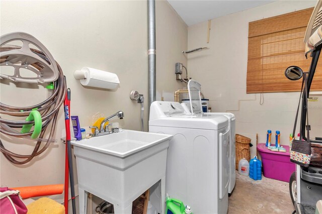 clothes washing area with laundry area, washer and clothes dryer, a sink, and concrete block wall