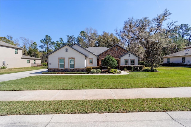 view of front of house with a front yard, stone siding, and stucco siding