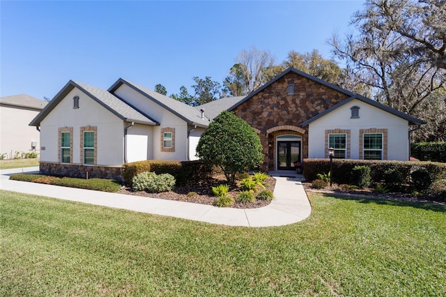 ranch-style house with a front yard, french doors, and stone siding