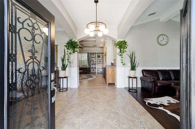 entryway with vaulted ceiling with beams, arched walkways, tile patterned flooring, wainscoting, and a notable chandelier