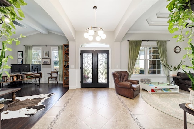 tiled entryway with an inviting chandelier, a wainscoted wall, lofted ceiling with beams, and plenty of natural light