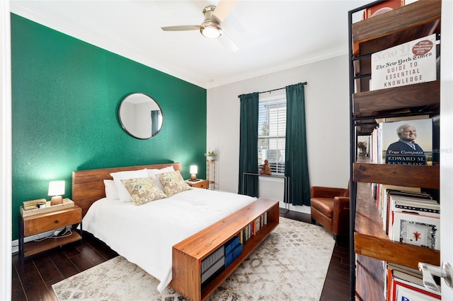 bedroom featuring an accent wall, wood finished floors, crown molding, and a ceiling fan