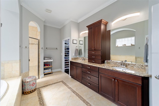 full bathroom featuring a spacious closet, a stall shower, a garden tub, and a sink