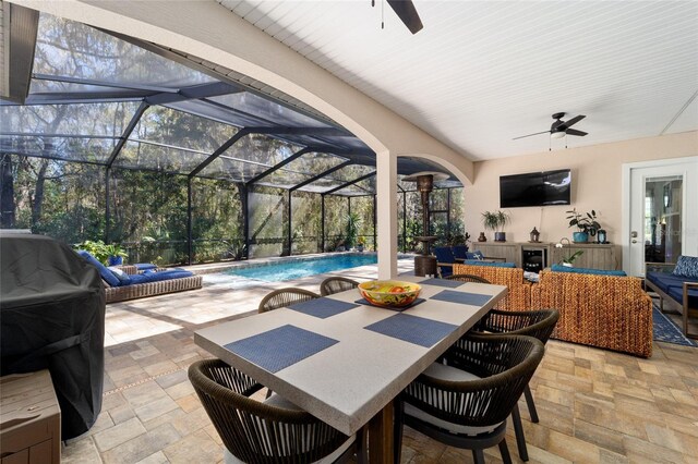 view of patio with glass enclosure, ceiling fan, outdoor dining space, and an outdoor pool