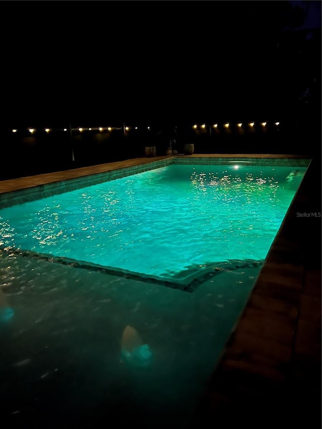 pool at twilight with a fenced in pool