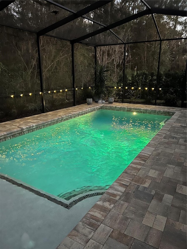 outdoor pool with a patio and glass enclosure