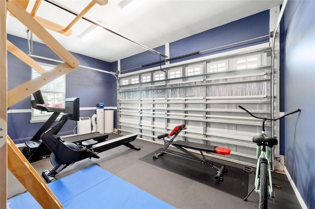 exercise area featuring a garage, a wealth of natural light, and baseboards