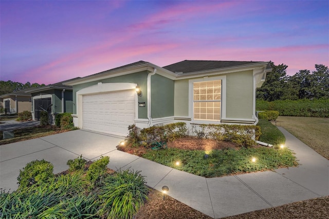 ranch-style house with a garage, concrete driveway, and stucco siding