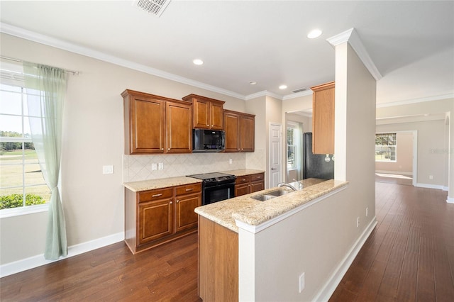 kitchen featuring dark wood-type flooring, visible vents, brown cabinets, black appliances, and tasteful backsplash