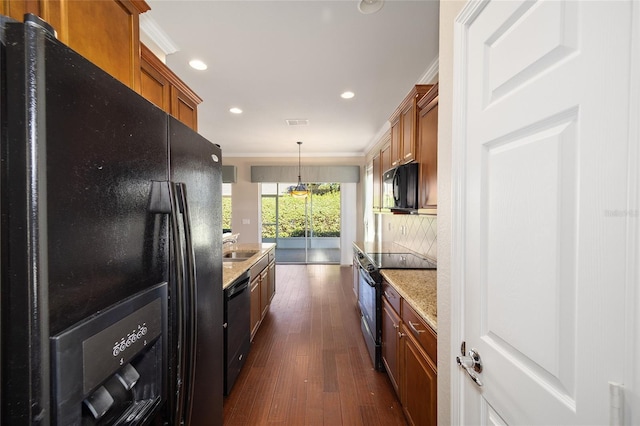 kitchen with decorative backsplash, ornamental molding, brown cabinets, dark wood-type flooring, and black appliances