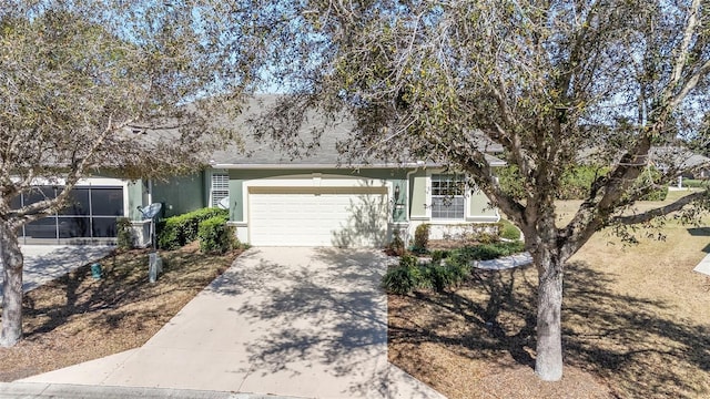 view of property hidden behind natural elements featuring an attached garage, driveway, and stucco siding