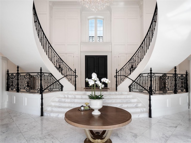 foyer entrance featuring stairs, marble finish floor, and a decorative wall