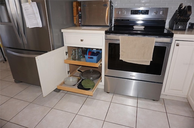 kitchen with light tile patterned floors, light countertops, appliances with stainless steel finishes, and white cabinets