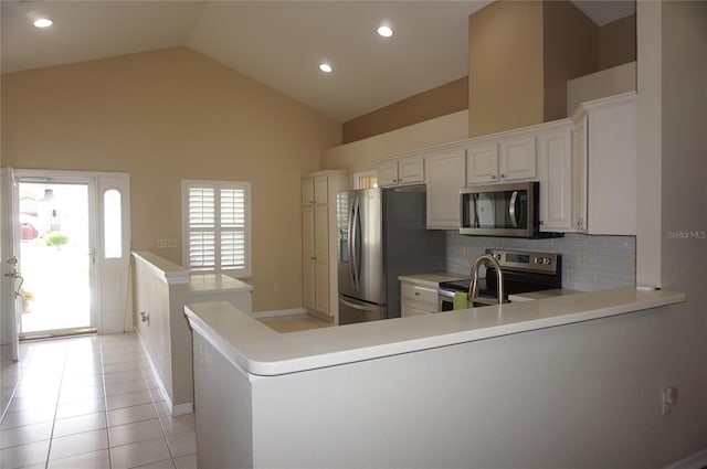 kitchen with appliances with stainless steel finishes, backsplash, a peninsula, high vaulted ceiling, and light countertops
