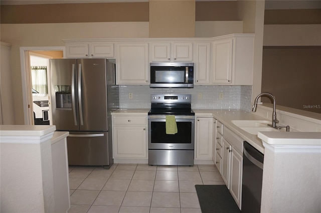 kitchen with appliances with stainless steel finishes, a sink, white cabinetry, light countertops, and tasteful backsplash