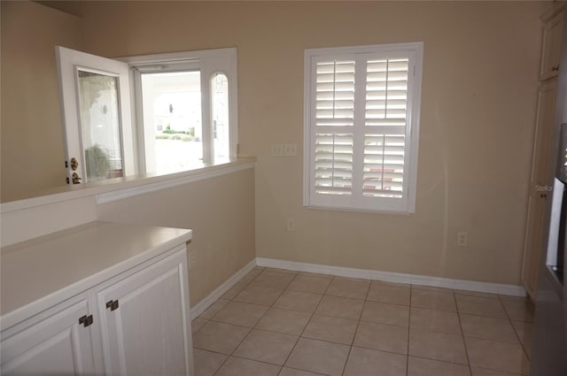 unfurnished dining area featuring baseboards and light tile patterned floors