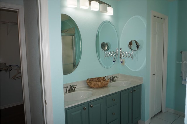 bathroom featuring double vanity, tile patterned flooring, a spacious closet, and baseboards