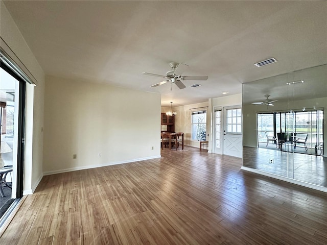 unfurnished room with ceiling fan with notable chandelier and wood-type flooring