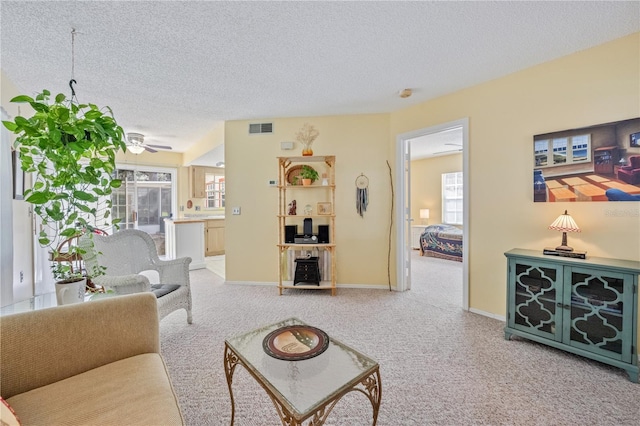 living room featuring ceiling fan, carpet flooring, and a textured ceiling