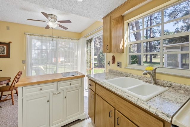 kitchen featuring white cabinets, ceiling fan, sink, and a textured ceiling