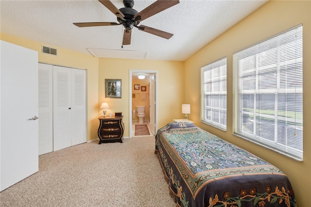 bedroom featuring a closet, ensuite bath, carpet floors, a textured ceiling, and ceiling fan