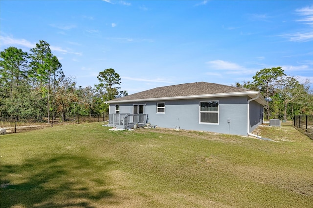 rear view of property with a deck, central air condition unit, and a yard