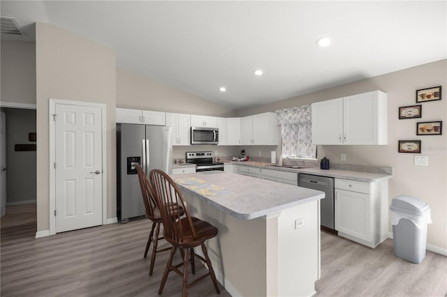 kitchen with sink, a center island, white cabinetry, stainless steel appliances, and a breakfast bar area