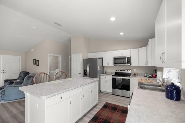 kitchen featuring appliances with stainless steel finishes, light hardwood / wood-style flooring, a center island, sink, and white cabinetry