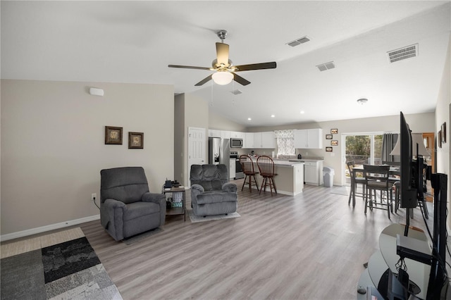 living room featuring vaulted ceiling, ceiling fan, and light hardwood / wood-style flooring