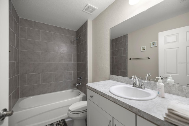 full bathroom featuring tiled shower / bath combo, vanity, toilet, and a textured ceiling