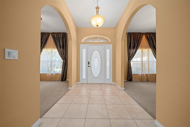 entryway with light carpet, a healthy amount of sunlight, and light tile patterned floors