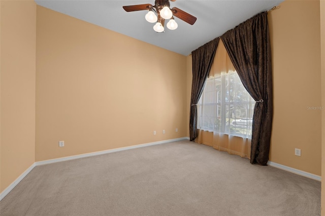 spare room featuring light carpet, baseboards, and a ceiling fan