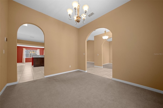 unfurnished room featuring arched walkways, light tile patterned floors, visible vents, light carpet, and baseboards