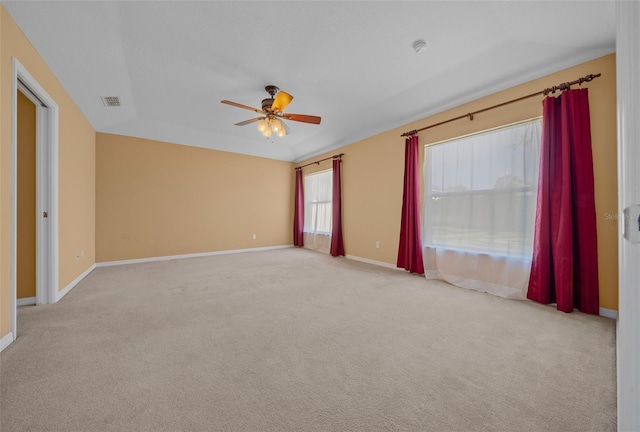 spare room with light colored carpet, visible vents, ceiling fan, and baseboards