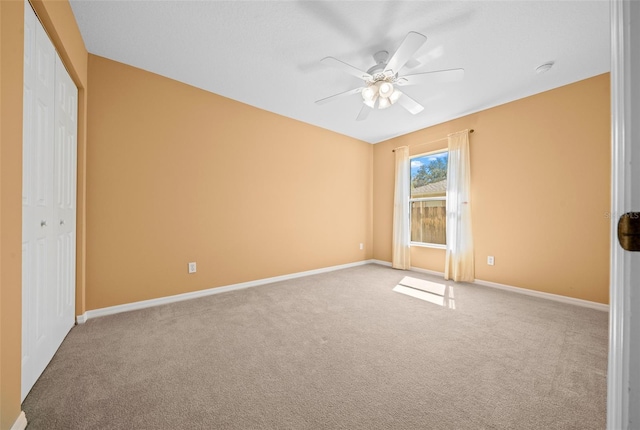 unfurnished bedroom with light carpet, a closet, a ceiling fan, and baseboards