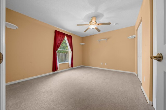 unfurnished room featuring light colored carpet, ceiling fan, and baseboards