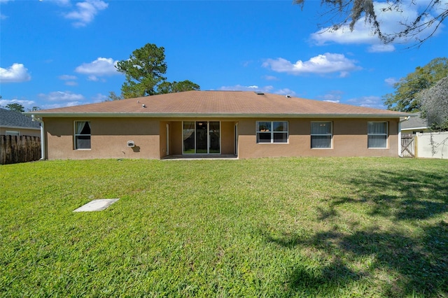 back of house featuring a yard, fence, and stucco siding