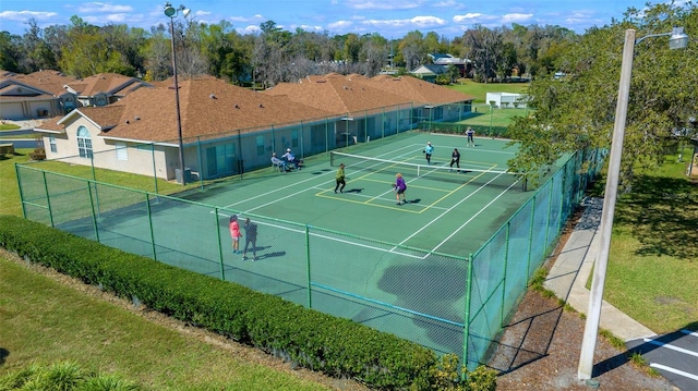 view of tennis court featuring a yard, a residential view, and fence